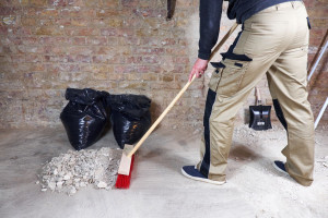 Worker sweeping rubble and dust with broom