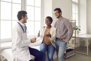 Happy young couple planning pregnancy and meeting with their doctor for health check