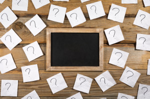 Question marks on crumpled note paper around a small blank black