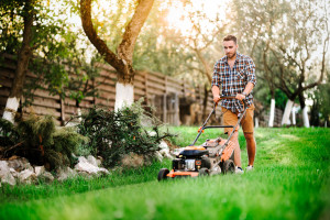 Close up details of landscaping and gardening. Worker using industrial manual lawnmower