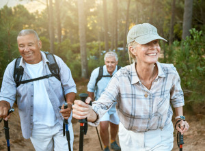 Hiking retired, elderly and senior friends or tourists in forest or mountains for fitness, health and wellness at old age. Diverse group of active mature pensioners outdoors on weekend hike in nature