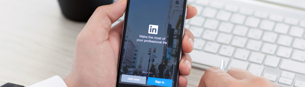 Businessman holding iPhone 6 Space Gray with service LinkedIn