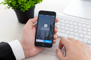 Businessman holding iPhone 6 Space Gray with service LinkedIn