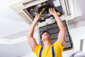 Repairman repairing ceiling air conditioning unit