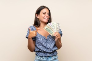 Young girl over isolated background taking a lot of money
