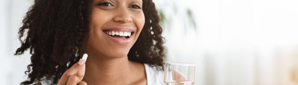 Healthy Diet Nutrition. Smiling Afro Woman Holding Vitamin Pill And Mineral Water