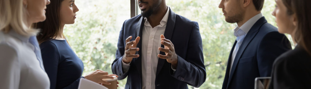 Confident African male leader telling diverse colleagues about new project
