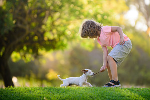 Kid with pets puppy. Happy child and dog hugs her with tenderness smiling.