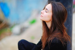 Portrait of a dreamy cute happy woman worker meditating outdoors with big eyes closed, sitting with the effect of blur closeup. De stress relief fit exercise, easy train enjoy career rest time concept