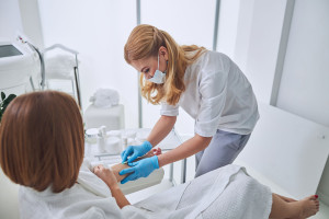 Beautiful elegant physician in white uniform during medical procedure in welness center