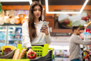 Arabic Young Woman Using Smartphone Application Shopping Groceries In Supermarket