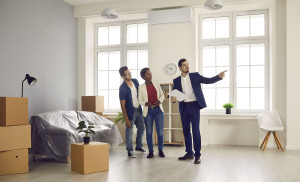 Real estate agent shows stylish modern house to married couple who is going to buy home.