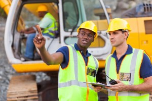 20022597 - co-workers talking at construction site with bulldozer behind them