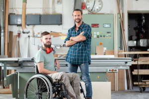 worker in wheelchair in a carpenter's workshop with his colleagu