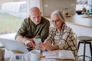 Stressed senior couple calculate expenses or planning budget together at home.