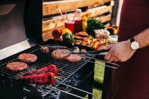 Chef cooking patties and vegetables grilled for outdoors barbecue