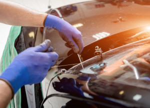 Automobile special workers remove old windscreen of a car in auto service
