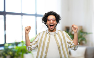 happy man in glasses celebrating victory at home