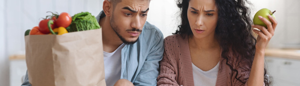 Frustrated Arab Spouses Sitting In Kitchen Checking Bills After Grocery Shopping