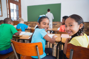 Cute pupils smiling at camera in classroom at the elementary school