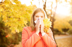 Girl with cold rhinitis on autumn background. Fall flu season. I