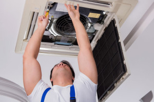 Worker repairing ceiling air conditioning unit