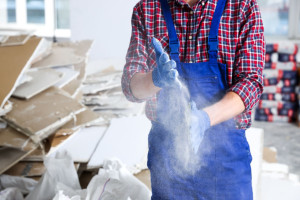 Construction worker shaking off dust from hands in room prepared