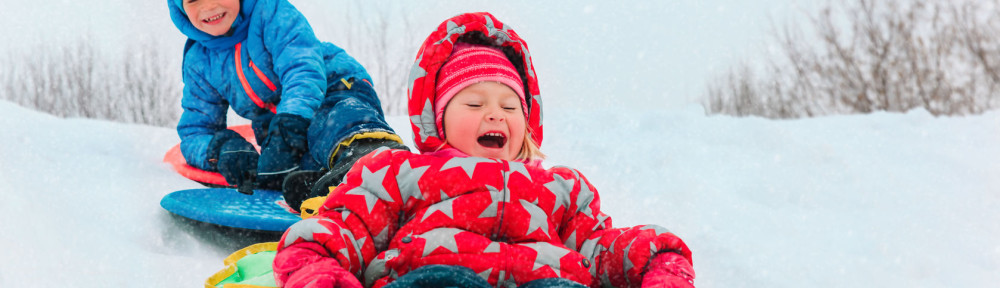 little boy and girl sliding in winter snow