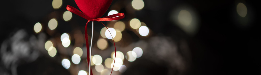 The girl holds red heart in hand on a bokeh background