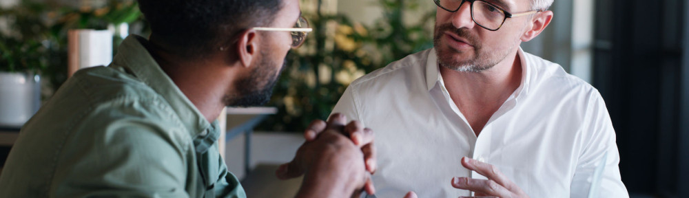 A dynamic duo that gets things done. two businessmen using a laptop and having a discussion in a modern office.