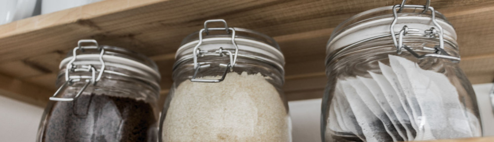 Tea, coffee and sugar in preserving jars on wooden shelf.