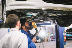 Mechanic holding clipboard with car owner in the workshop garage