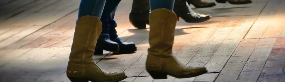 Western folk music dancer's legs in cowboy boots dancing on a wooden old floor