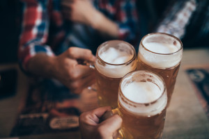 people, men, leisure, friendship and celebration concept - happy male friends drinking beer and clinking glasses at bar or pub