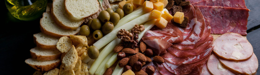 Assorted from meat and cheese on a chopping board. Smoked sausage, meat roll from a turkey with cheese, jamon, olives, nuts and various grades of cheese. Mediterranean traditional snack.