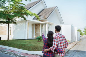 young couple standing in front of their new house