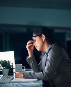 Overtime can come with headaches. Shot of a young businesswoman experiencing a headache in the office.