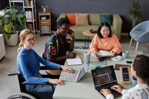 Young diverse IT team meeting at table in office and discussing project