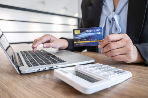 Businesswoman using laptop and holding credit card for paying de