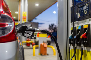 silver mettalic color car refueling on night gas station - close-up with selective focus and blurry background