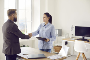 Female bank manager exchanging handshake with business client after meeting in office