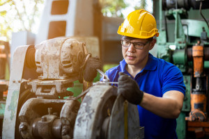 Man Industry wearing helmet safety working repair machine in fac