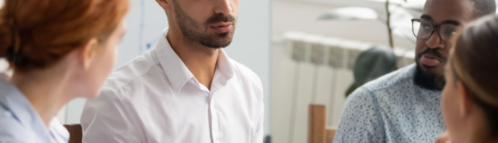 Serious businessman talking with group of business partners at meeting