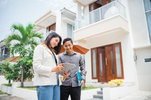 Asian couple using pads and clipboards in a residential background