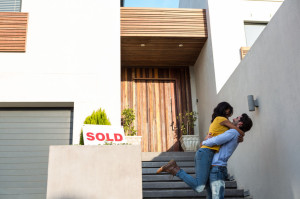 Happy Hispanic couple hugging in front of new house