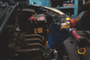 Hand of a professional car mechanic refilling engine oil