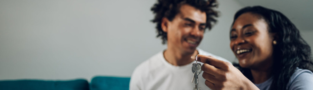 African american couple holding home keys in their new apartment