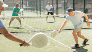 Adult and elderly men playing padel against two men