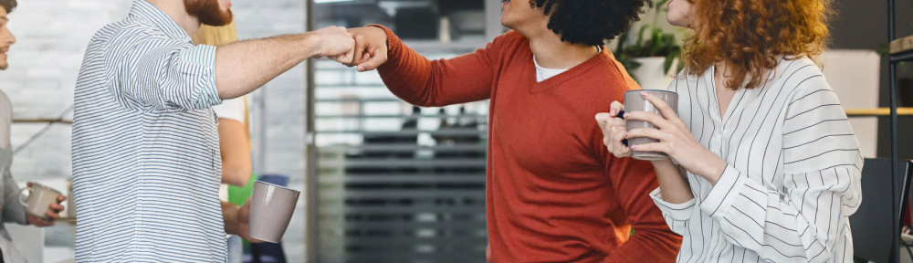 Happy male colleagues giving fist bump during coffee break