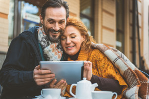 Loving couple using gadget in cafeteria